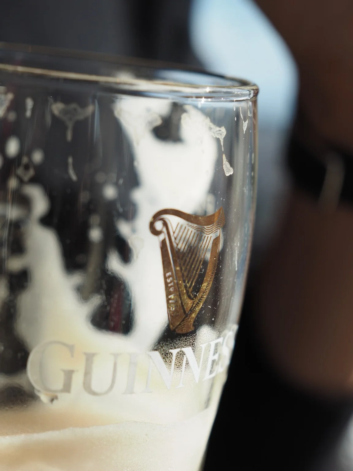 A close view of a Guinness glass, its harp and the traces of foam.