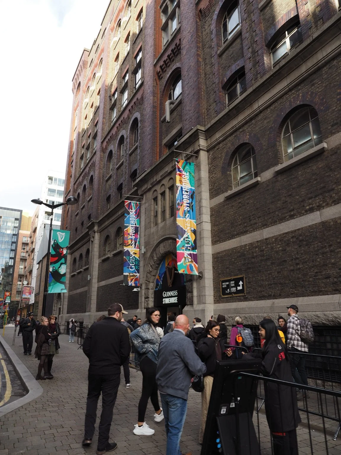 The Guinness Storehouse facade and colourful banners above visitors at the entrance.